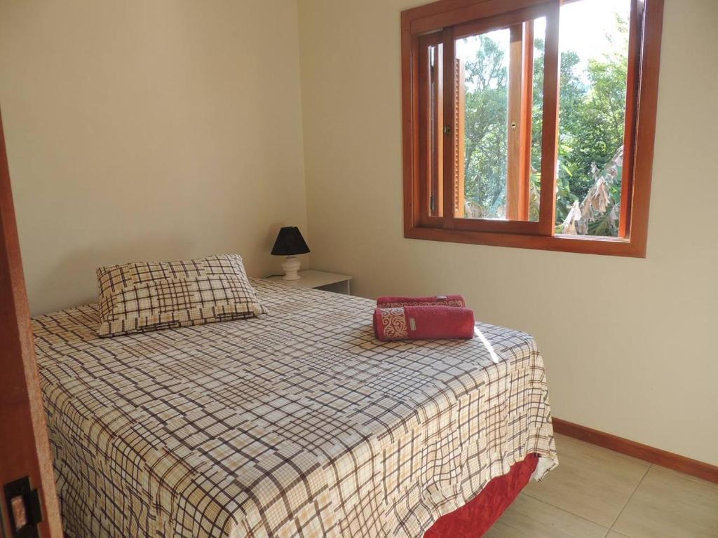 a bedroom with a bed and a window at Chale Recanto do Belvedere in Gramado
