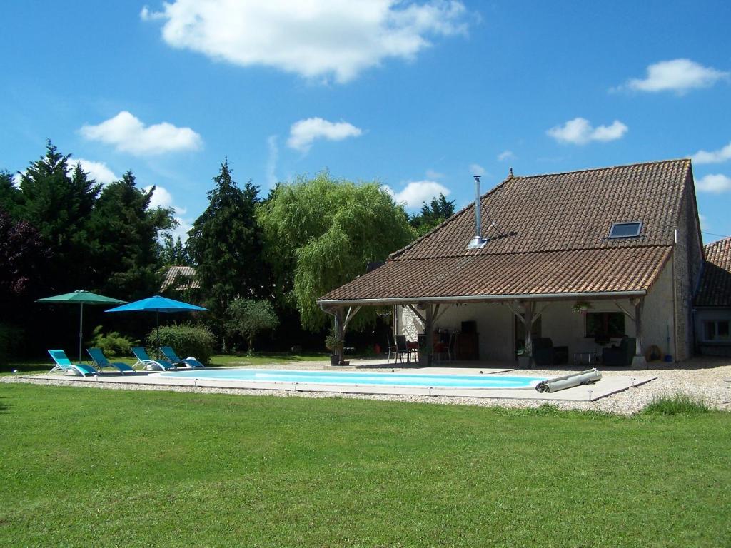 une maison avec une piscine entourée de chaises et de parasols dans l'établissement Chez Jousseaume Chambre d'Hôtes et Gites, à Saint-Ciers-Champagne