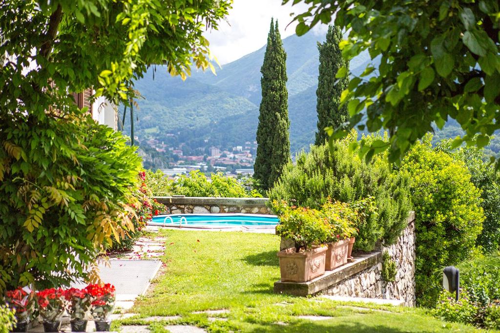 a garden with a swimming pool and mountains in the background at J&J House in Castelmarte