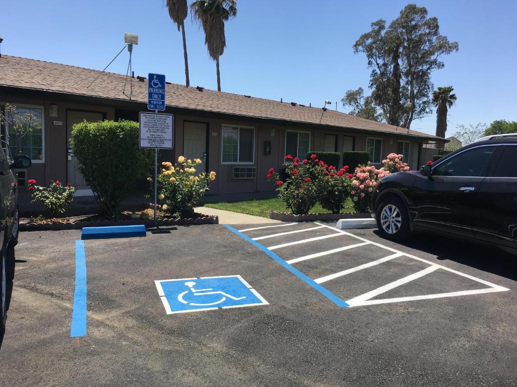 a parking lot with a handicapped sign in front of a building at Maple Inn and Suites Los Banos in Los Banos
