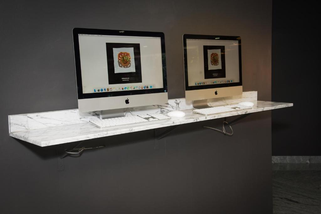 A wall-mounted marble-look shelf with two desktop computers.