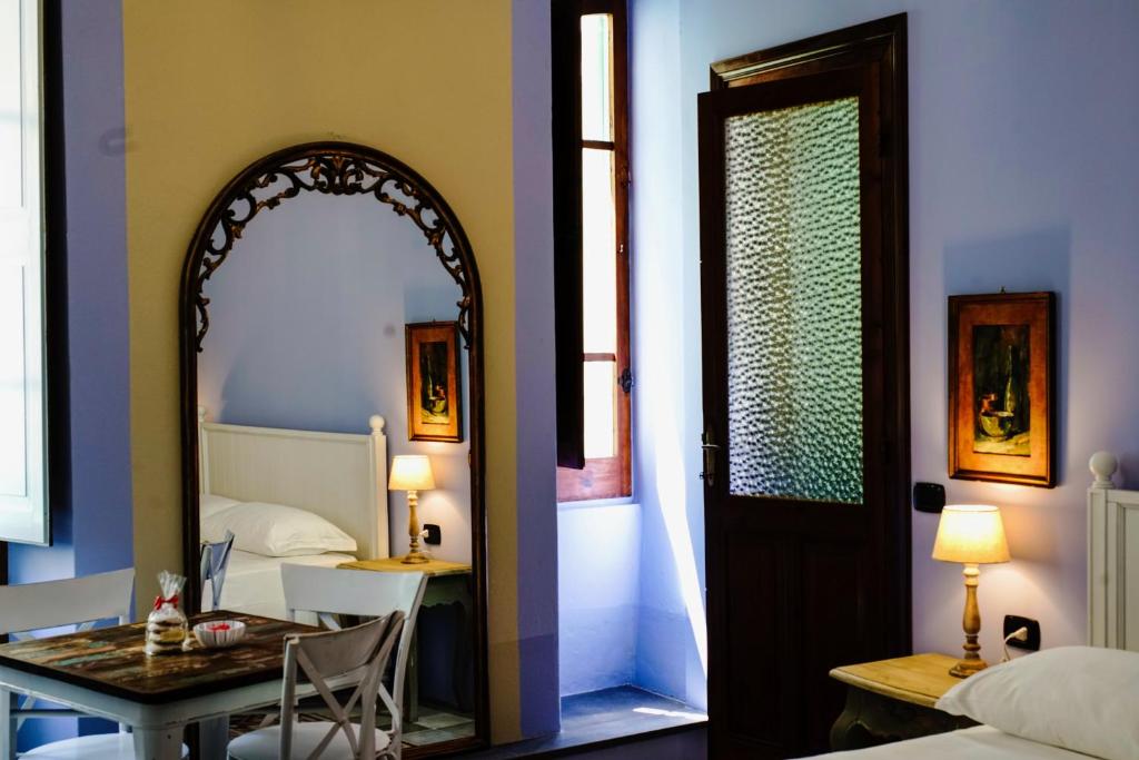 Pokój z łóżkiem, stołem i lustrem w obiekcie Sofia Family Suites w mieście Carloforte