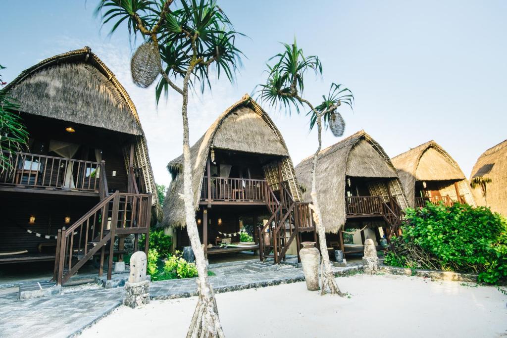 a group of huts on the beach with palm trees at Dream Beach Huts in Nusa Lembongan