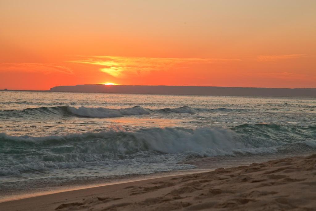 a sunset on the beach with the ocean at Zahara Sol Villas y Apartamentos by QHotels in Zahara de los Atunes