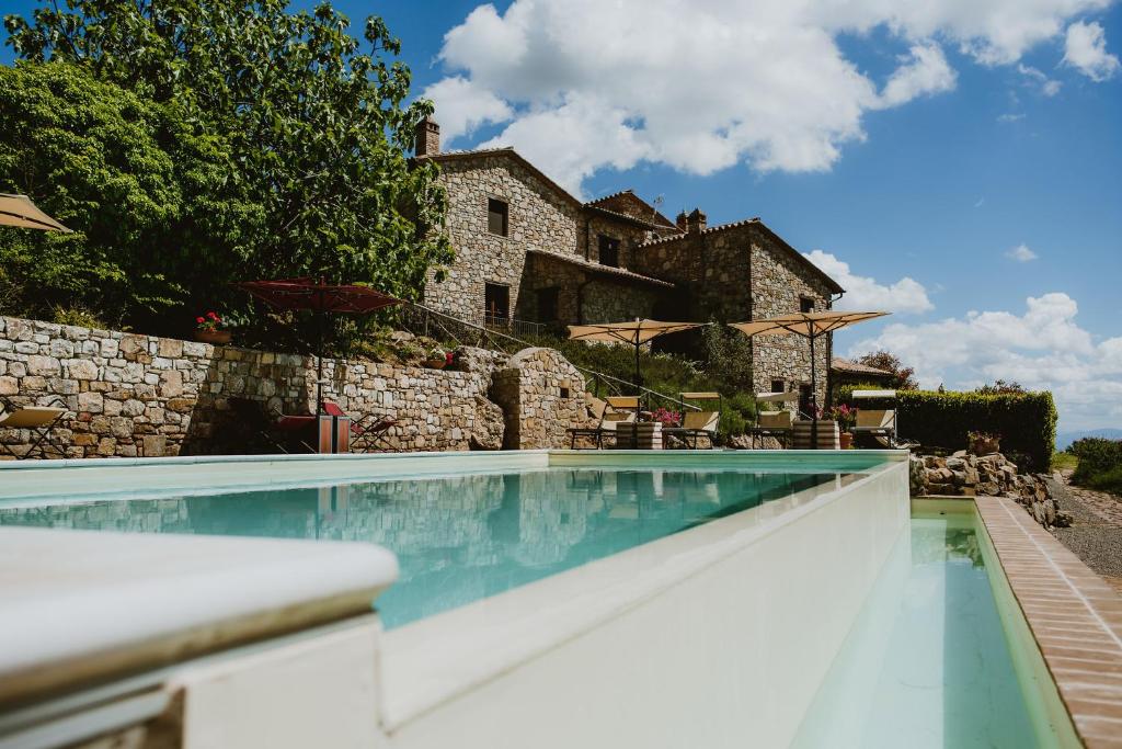 a swimming pool in front of a stone house at I Casali Di Colle San Paolo in Tavernelle