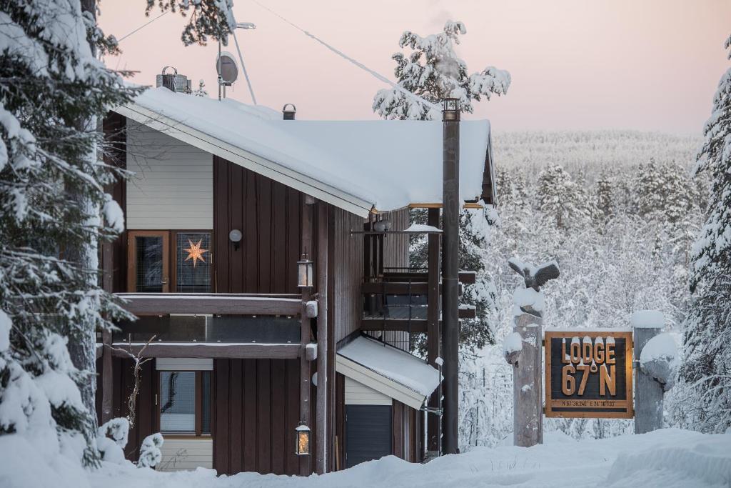 une maison dans la neige avec un panneau devant elle dans l'établissement Lodge 67°N Lapland, à Äkäslompolo