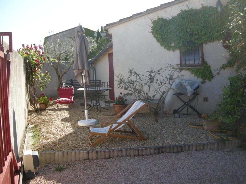 een patio met een tafel, een parasol en stoelen bij Chambre d'hôtes Esterelle in Pernes-les-Fontaines