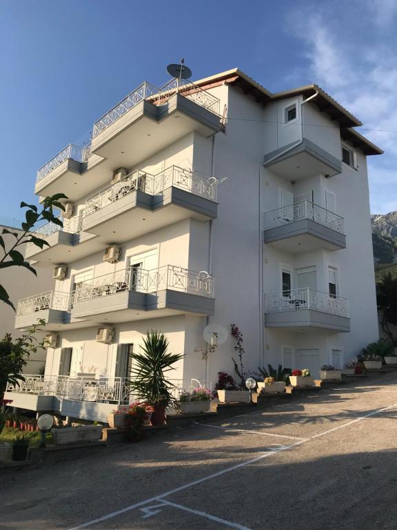 un gran edificio blanco con balcones y flores en un aparcamiento en Villa 61 Sea and Sunset View, en Dhërmi