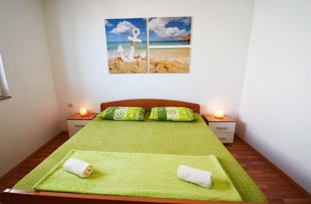 a bedroom with a bed with green sheets and two candles at Apartments Barbati in Kustići