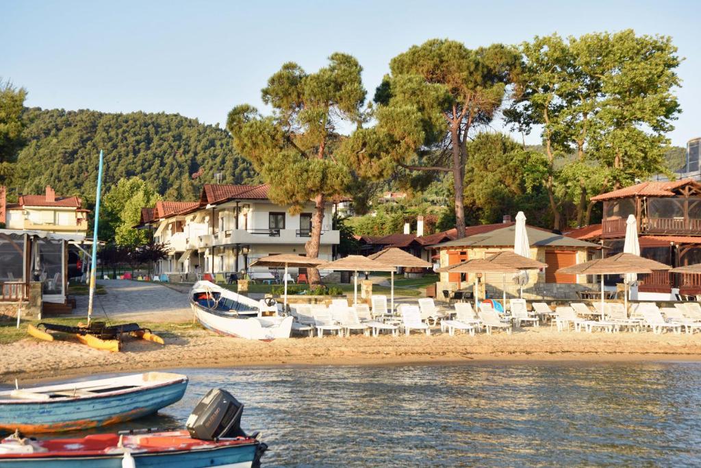 two boats sitting on the shore of a beach at Haus Platanos Apartments & Bungalows by the Sea in Vourvourou