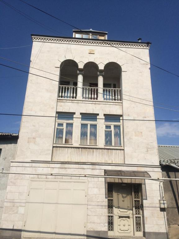 a tall white building with two windows and a balcony at Guest House Lilia in Yerevan