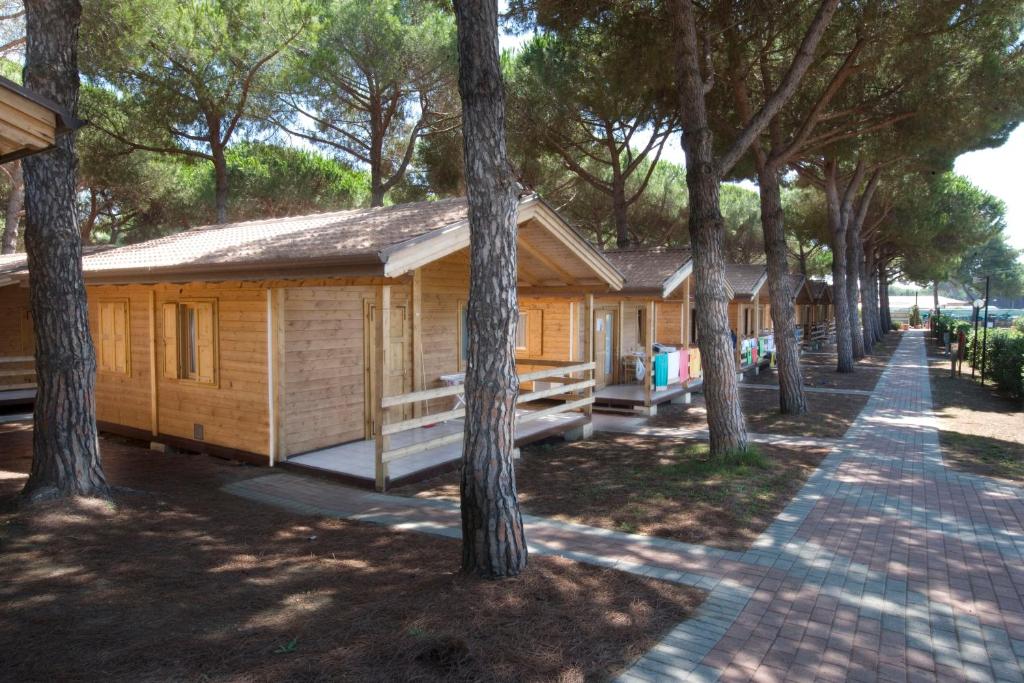 eine Reihe von Cottages aus Holz umgeben von Bäumen in der Unterkunft Camping Village Africa in Albinia