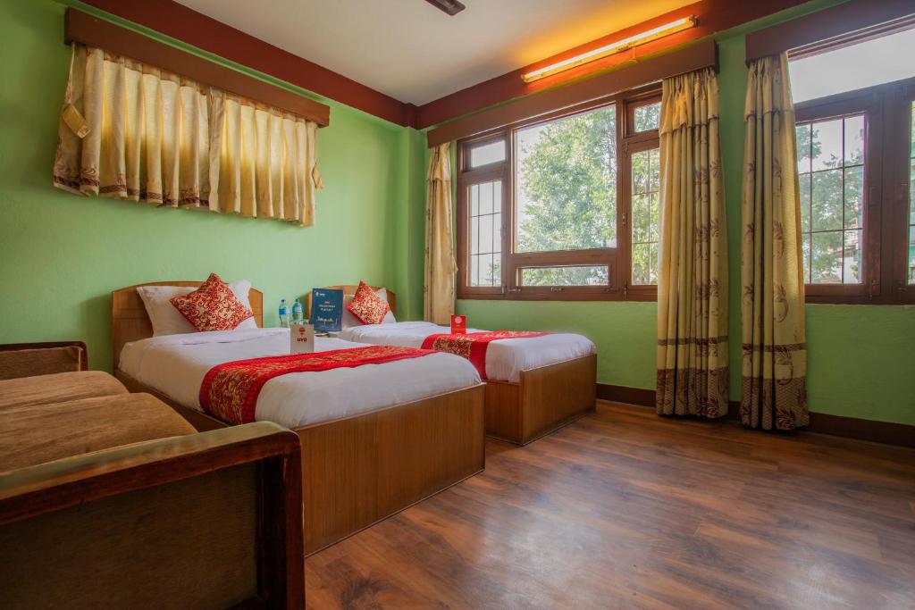 two beds in a room with green walls and windows at Hotel Green Orchid in Kathmandu