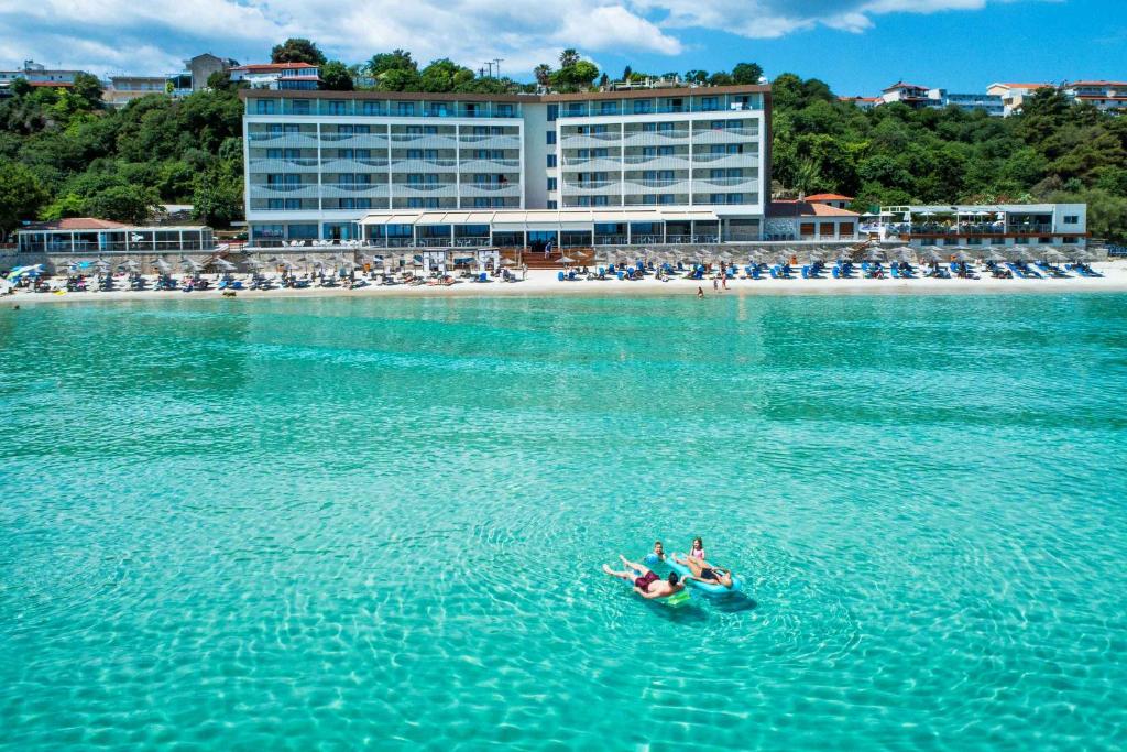 two people in a boat in the water near a beach at Ammon Zeus Luxury Beach Hotel in Kallithea Halkidikis