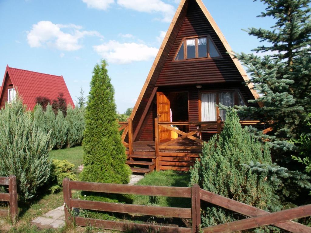 ein Blockhaus mit einem Zaun und Bäumen in der Unterkunft Domek letniskowy in Antonowo