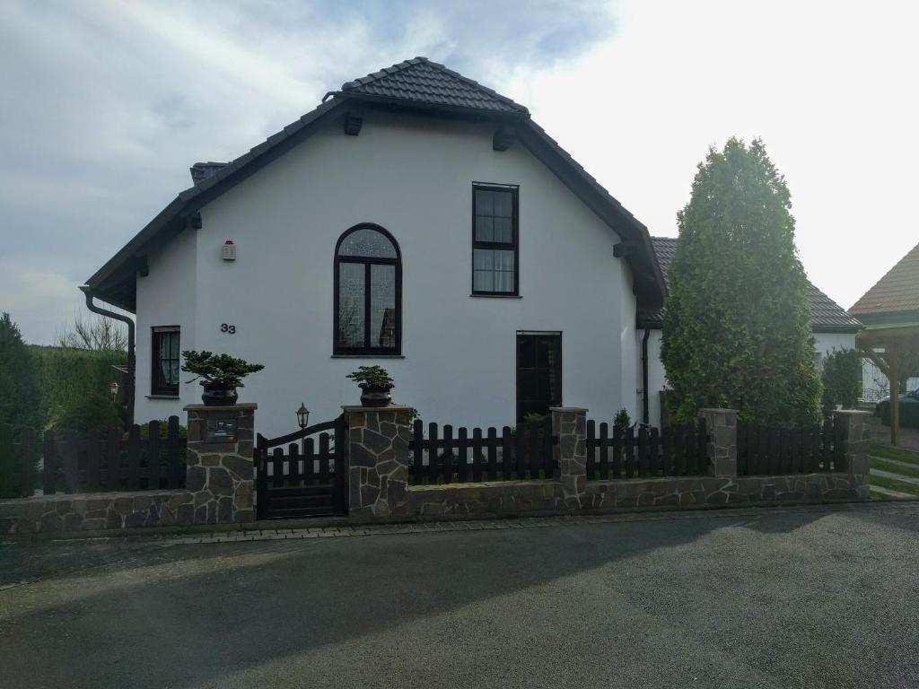 ein weißes Haus mit einem Zaun davor in der Unterkunft Ferienwohnung mit Terrasse in Grimma