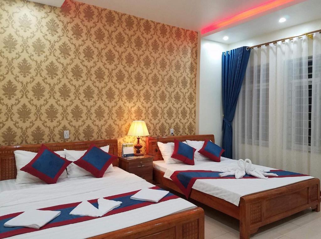 a bedroom with two beds and a window at Ahoj Guest House in Ha Long