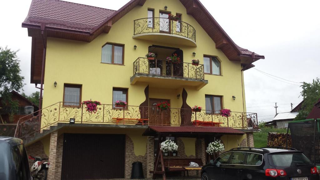 una casa amarilla con balcones y un coche aparcado delante en Casa Paty, en Mănăstirea Humorului