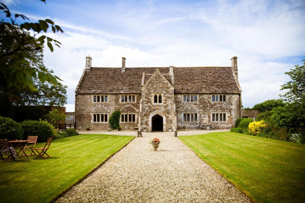 una antigua casa de piedra con césped verde en Seymours Court en Frome