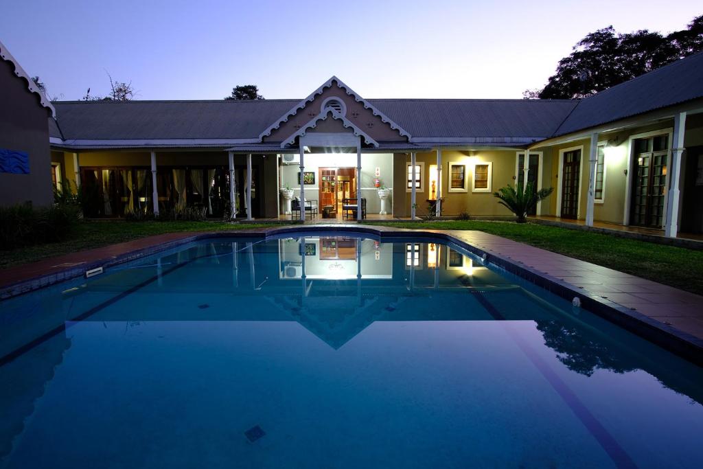 a swimming pool in front of a house at night at Cu Guest House in Phalaborwa