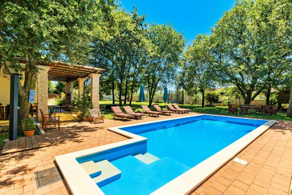 a swimming pool with chairs and trees in a yard at Holiday Home Sarita in Šišan