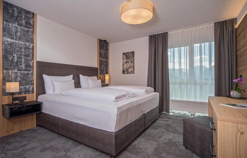 a bedroom with a large bed and a window at Arthur's Hotel und Apartments am Achensee in Maurach