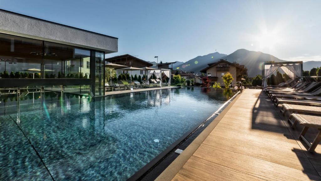 una piscina en un complejo con montañas en el fondo en Hotel Sun, en Naz-Sciaves