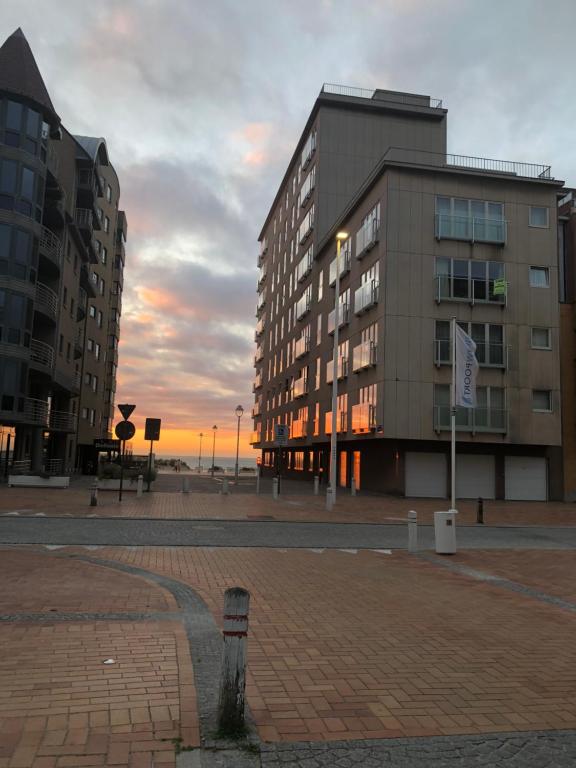 a building in a city with a sunset in the background at Nieuwpoortnachten res. Westdiep Dominique in Nieuwpoort