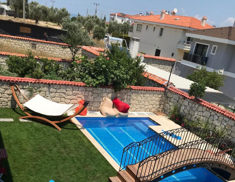 a swimming pool in a yard with two chairs and a house at Grand Alaçatı Butik Hotel in Alaçatı