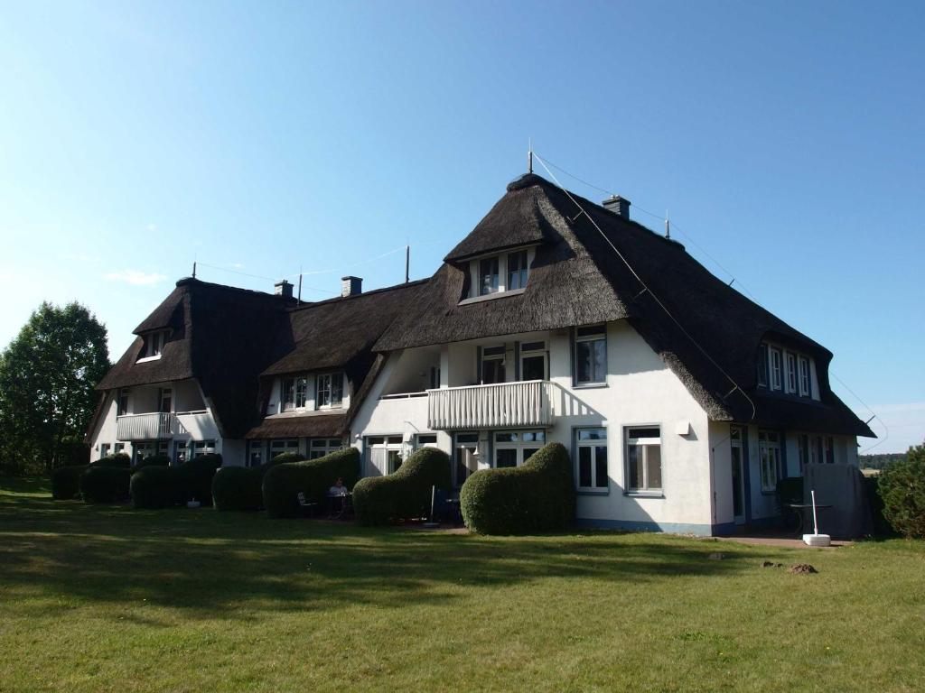 a large white house with a thatched roof at Landhaus am Haff_ Wohnung B 8 in Stolpe auf Usedom