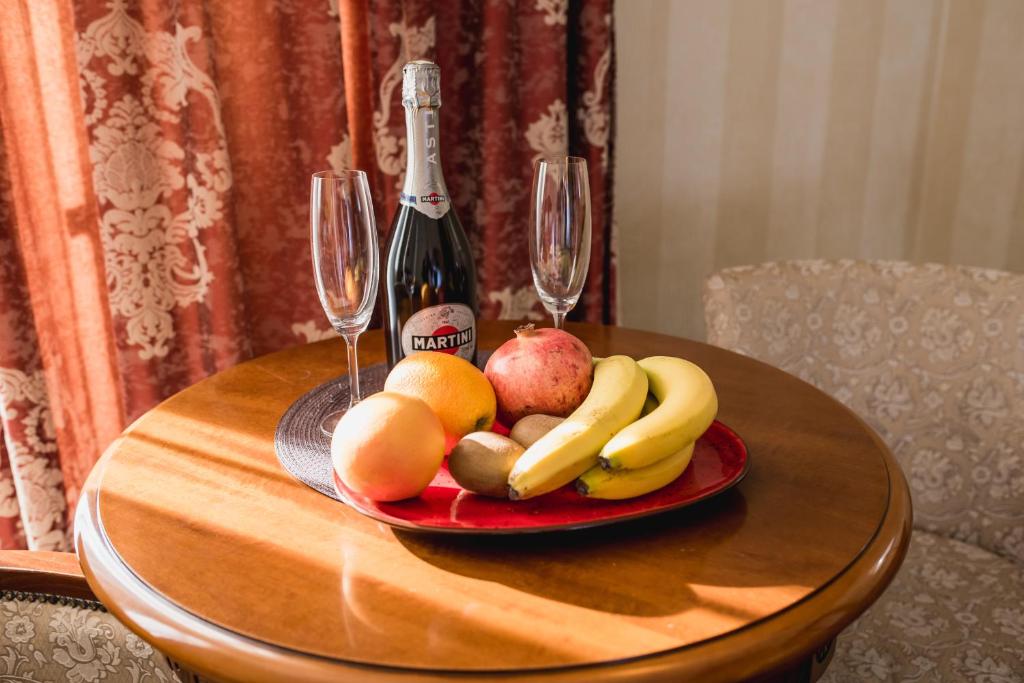 a plate of fruit on a table with a bottle of champagne at Hotel Sofia in Polyana