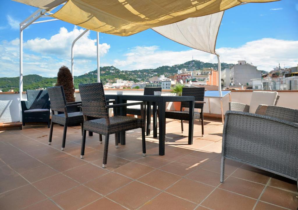 um pátio com uma mesa, cadeiras e um guarda-sol em Hostal Julieta em Lloret de Mar