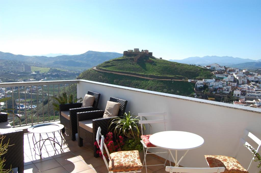 een balkon met banken en tafels en een heuvel bij The Penthouse in Alora