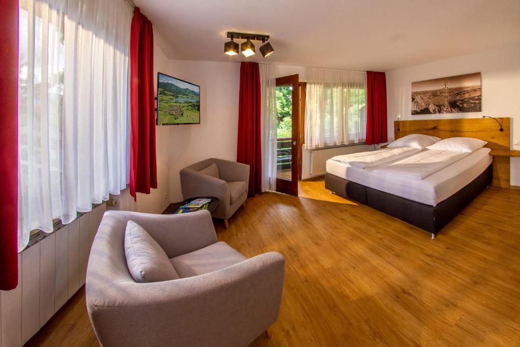 a bedroom with a bed and a couch and chairs at Appartement-Hotel-Allgayer in Oy-Mittelberg