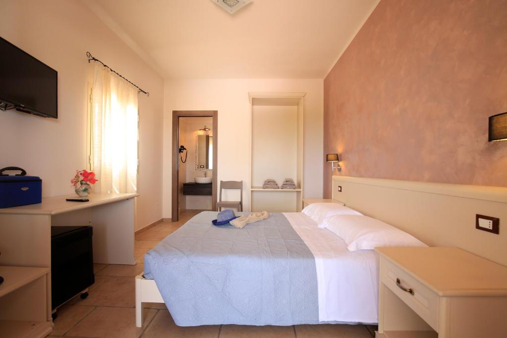 a bedroom with a white bed and a television at B&B Hibiscus in Vieste