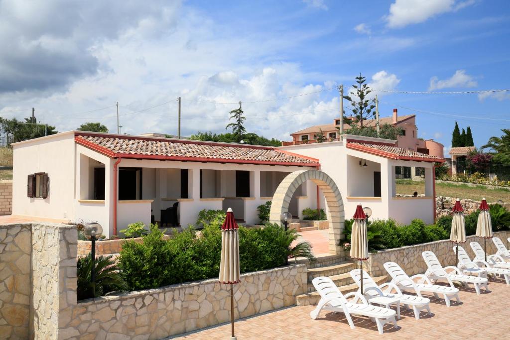 a row of chairs and umbrellas in front of a house at B&B Hibiscus in Vieste