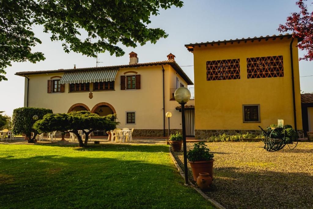 une grande maison jaune avec une cour devant elle dans l'établissement Agriturismo Bellosguardo, à Reggello