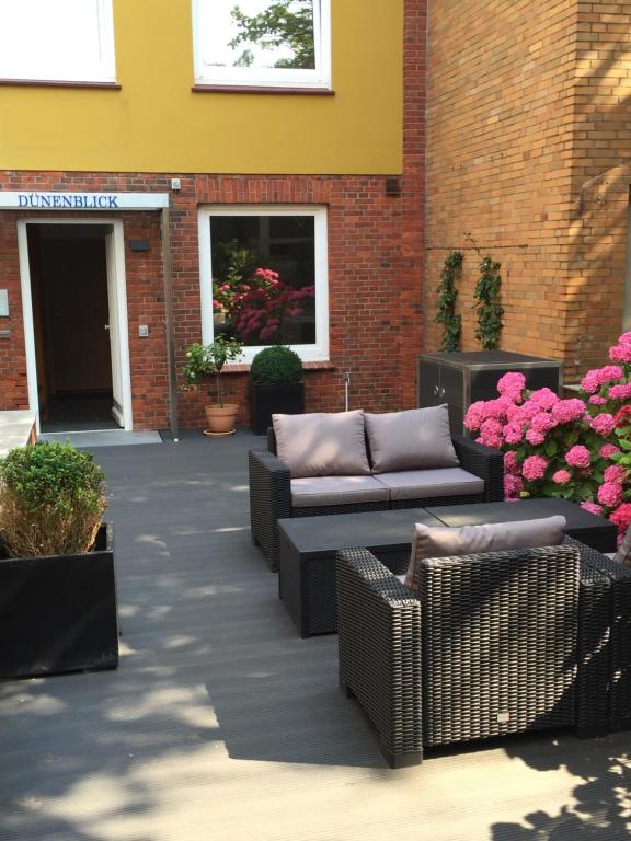 a patio with couches and flowers in front of a building at Dünenblick Apartments in Helgoland