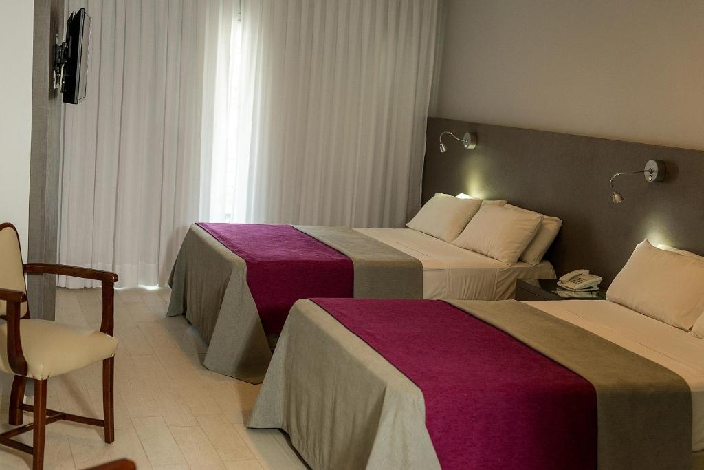una habitación de hotel con 2 camas y una silla en Termas de Miraflores Hotel Termal en Termas de Río Hondo