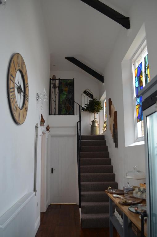 korytarz ze schodami i zegarem na ścianie w obiekcie The Old Chapel Boutique B&B w mieście Towcester