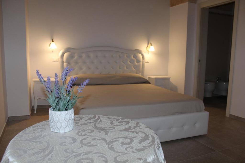 1 dormitorio con cama y mesa con flores púrpuras en B&B Ilenia, en Oria