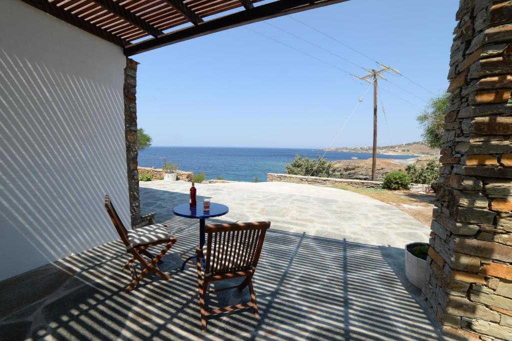 eine Terrasse mit einem Tisch, 2 Stühlen und Meerblick in der Unterkunft Villa Aphrodite in Koundouros