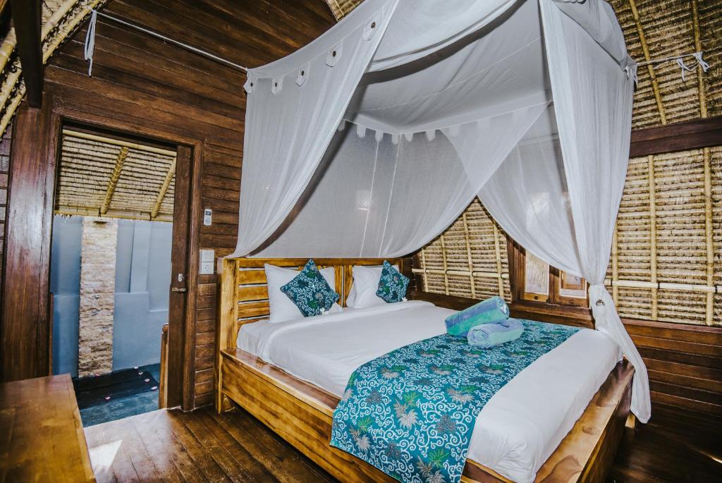 a bedroom with a bed with a mosquito net at Dream Beach Huts in Nusa Lembongan