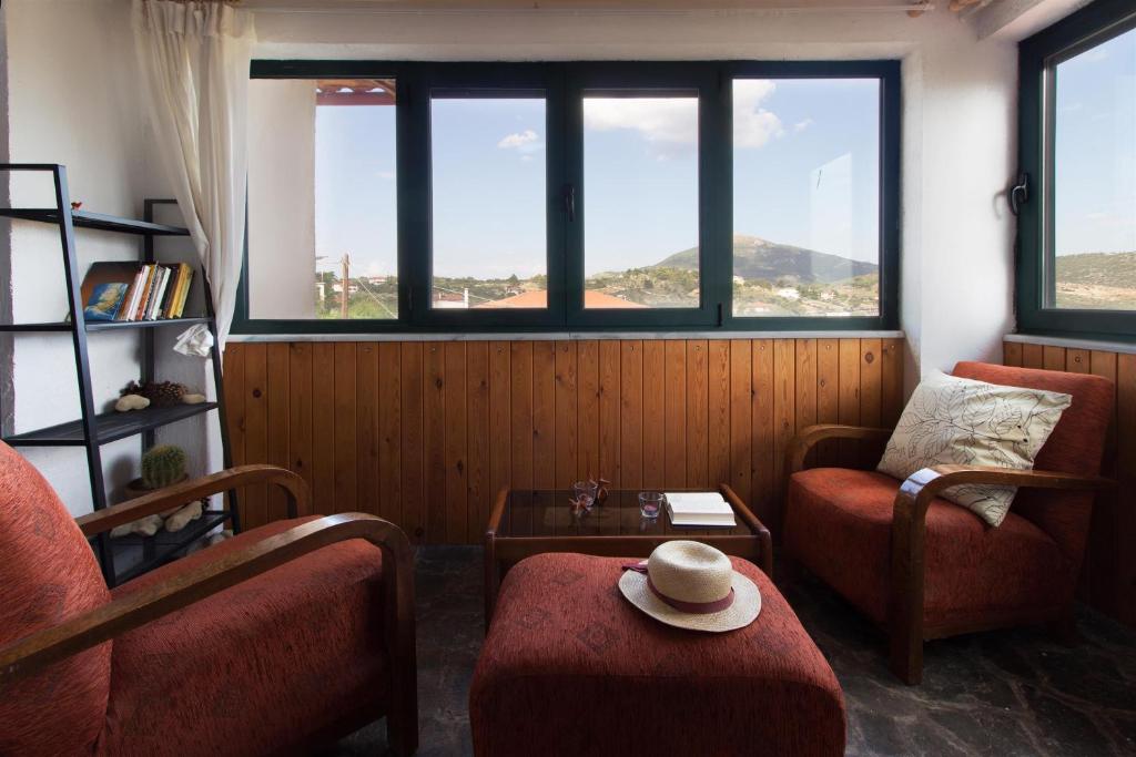 a living room with two chairs and a table and windows at Mavilia Traditional Guesthouse in Ligourio