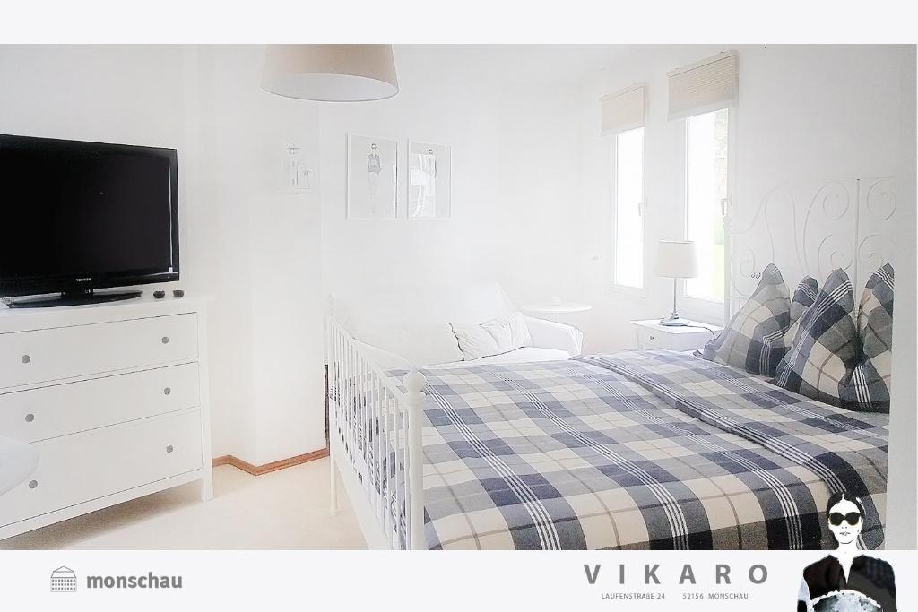 - une chambre blanche avec un lit et une télévision dans l'établissement Vikaro, à Monschau