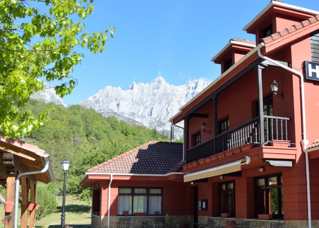 uma casa com varanda e montanhas ao fundo em Hotel El Jisu em Camaleño