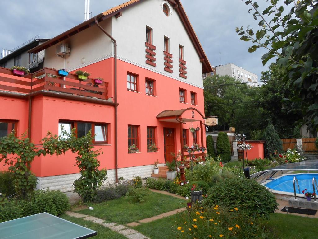 ein rotes und weißes Haus mit einem Garten in der Unterkunft Aranyeső Vendégház Csorbai in Budapest