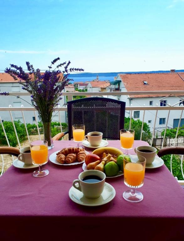 a table with food and drinks on a purple table cloth at Apartments Brčić in Kaštela