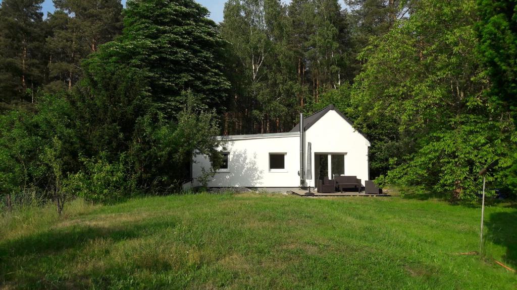 ein kleines weißes Haus mitten auf einem Feld in der Unterkunft Cottage am Wald bei Berlin in Falkensee