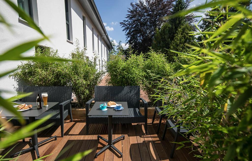 two tables and chairs on a patio with plants at Hotel Südstern in Munich
